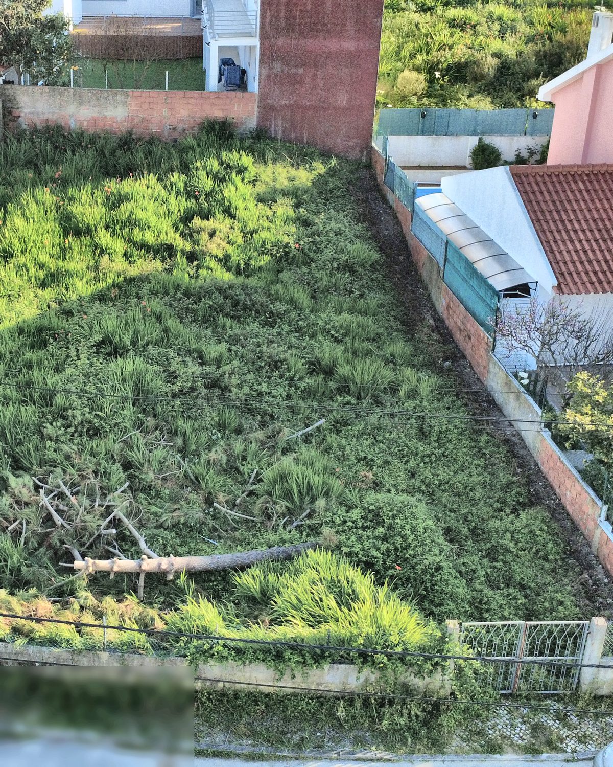 Vista aérea vertical de terreno urbano murado, com os limites do lote visíveis entre moradias