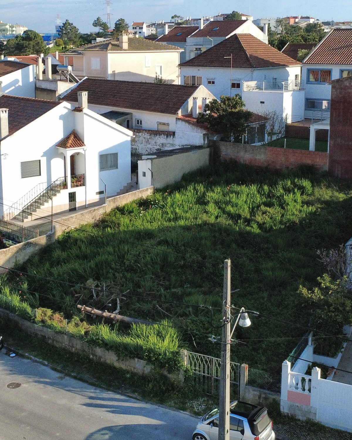 Vista aérea oblíqua do terreno e da frente de rua, com a envolvente residencial