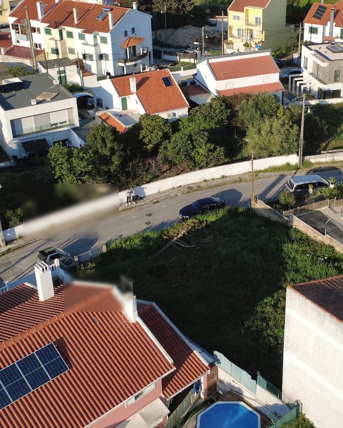 Enquadramento aéreo amplo do bairro, com o terreno em primeiro plano e o acesso rodoviário